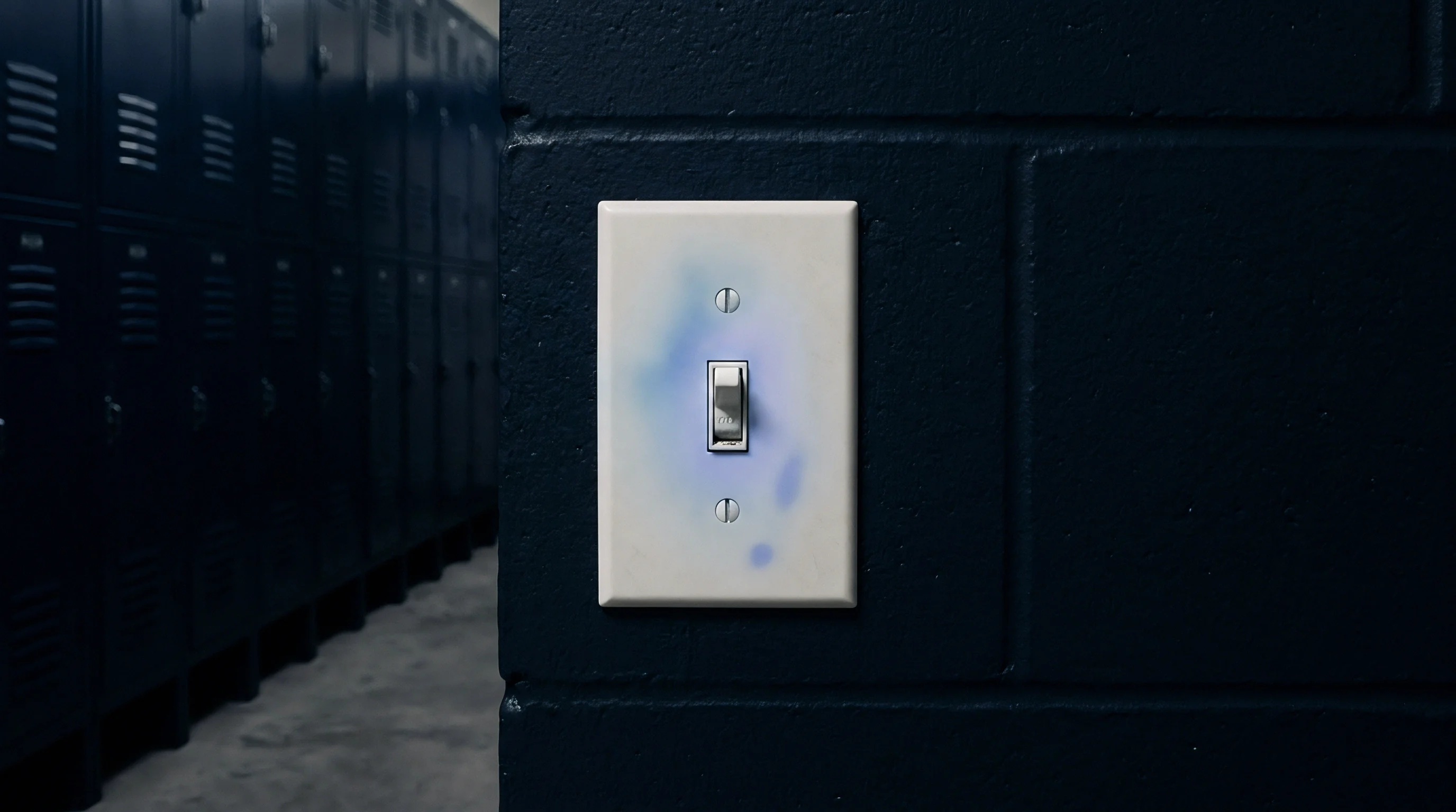 A light switch plate composed of injection moulded polymer exhibits localised discolouration and surface contamination against a dark masonry wall background.