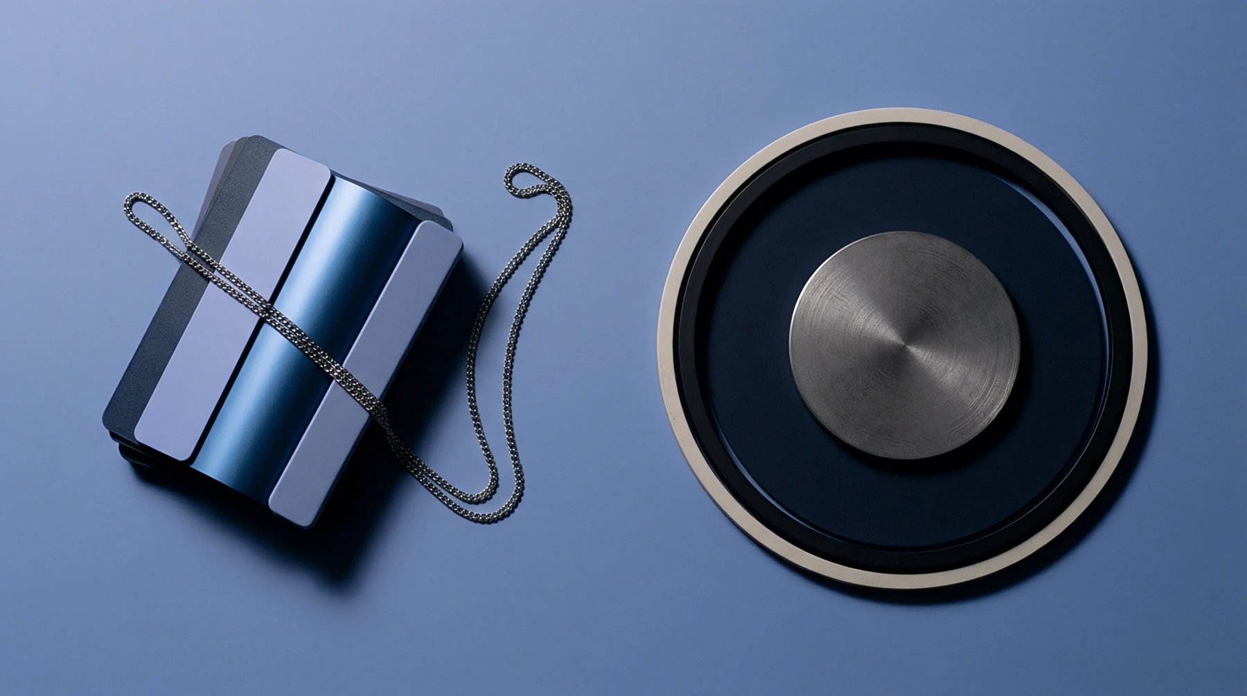 Molded polymer material swatches accompanied by a metallic chain and concentric circular components lie arranged on a matte blue production surface.